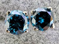 Front view of blue diamond studs in 14K white gold four-prong settings