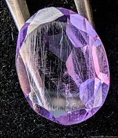 Close-up of oval purple faceted amethyst on black background