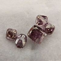 Five loose deep pink faceted diamonds on white background