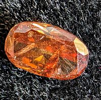 Oval faceted orange-brown diamond stone on black background