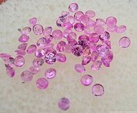 Group of small round faceted pink sapphires on off-white background