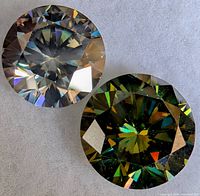 Two round brilliant moissanite stones side by side on white background