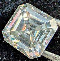 Square/Asscher-cut moissanite held by tweezers showing facets and clarity
