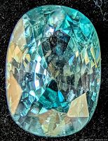 Front view of oval faceted blue zircon showing color and cut