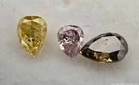 Three pear-cut fancy color diamonds on white background