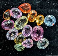 Close-up view of assorted loose faceted sapphires on black background