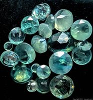Cluster of round faceted alexandrite gemstones showing greenish hue