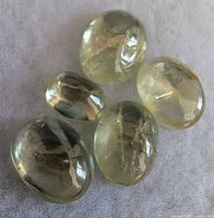 Five views of an oval pale yellow-green zultanite stone showing internal inclusions