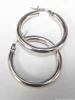 front view of two silver hoop earrings with clasps visible