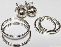 All three earring pairs laid out: faceted studs, large hoops, small hoops