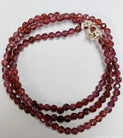 Coiled view of garnet bead necklace showing bead cut and clasp