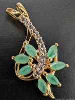 Front view of silver pendant with emeralds and clear stones