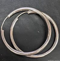 pair of silver hoop earrings stacked on black background