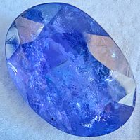 Front view of oval faceted blue-violet tourmaline gemstone showing facets and inclusions