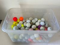 Overview of plastic tub filled with mixed golf balls