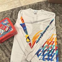 Shirt laid flat beside red Coca-Cola lunchbox