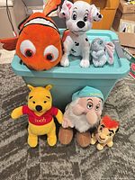 All six plush toys grouped on and in front of teal storage bin