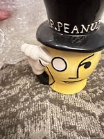 Front view of Mr. Peanut ceramic cookie jar with raised hand and top hat lid