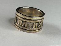 Full view of wide band ring showing Roman numerals design