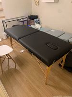 Assembled black massage table on wood legs