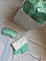 Open box showing multiple individually bagged blue silk sleep masks