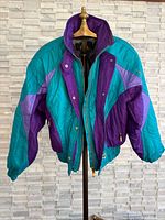 Front view of Descente teal and purple ski jacket on hanger