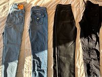 Four pairs of women’s pants laid flat: two blue denim, one black leather, one black cotton