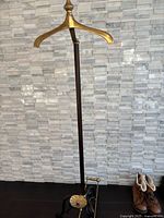 Full view of valet stand showing brass hanger, wooden pole and base
