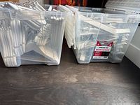 Two clear bins filled with white wooden hangers