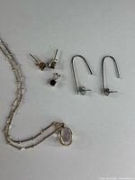 All six pieces laid out: chain with pendant, garnet studs, garnet pendant, U-shaped earrings