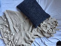 Oatmeal throw and navy pillow together on surface