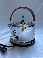 Side view of kettle showing mirror finish, handle, lid, power cord