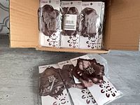 Open carton showing multiple Conair brown flower hair clips in original packaging