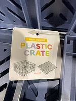 Tag showing product type 'Plastic Crate' attached to grey crate