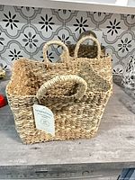 Two rectangular woven seagrass baskets with tags visible