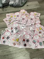 Pile of approximately 30 sealed packs of pink-carded Croc shoe charms on floor