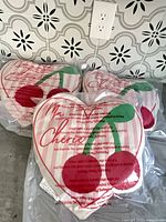 Three vacuum-sealed heart pillows on counter, cherry design visible