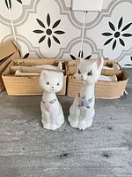 Front view of two cat figurines with boxes containing remaining sets behind