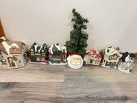 Line-up of six Christmas village pieces on floor