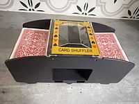 Front view of black automatic card shuffler with two red-back decks inserted