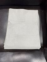 Folded grey pinstripe blackout curtain panel on dark background