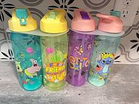 Front view of all four tumblers showing lids and graphics