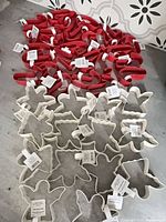 Red candy cane cookie cutters and white angel cookie cutters spread on floor