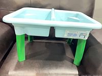 overall view of light blue dual-compartment table on green legs