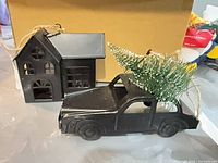 Both metal ornaments, house and truck, in front of box