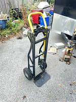 Full view of black and yellow steel hand truck dolly standing upright