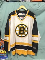 Front view of white Boston Bruins CCM hockey jersey with spoked-B crest and shoulder patch
