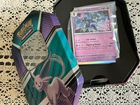 Tin opened showing stack of sleeved Pokémon cards, top card Ceruledge