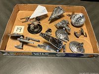 Overview of ten assembled metal spaceship models in cardboard tray