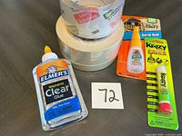 Group shot of all glue bottles, super glue packages, packaging tape roll and two masking tape rolls